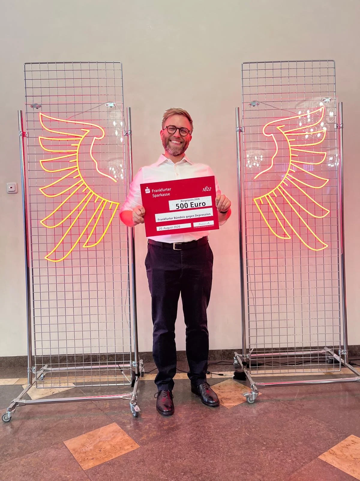 Sven Ganter holds the Citizens’ Award for the Frankfurt Alliance Against Depression between two illuminated Frankfurt eagle symbols