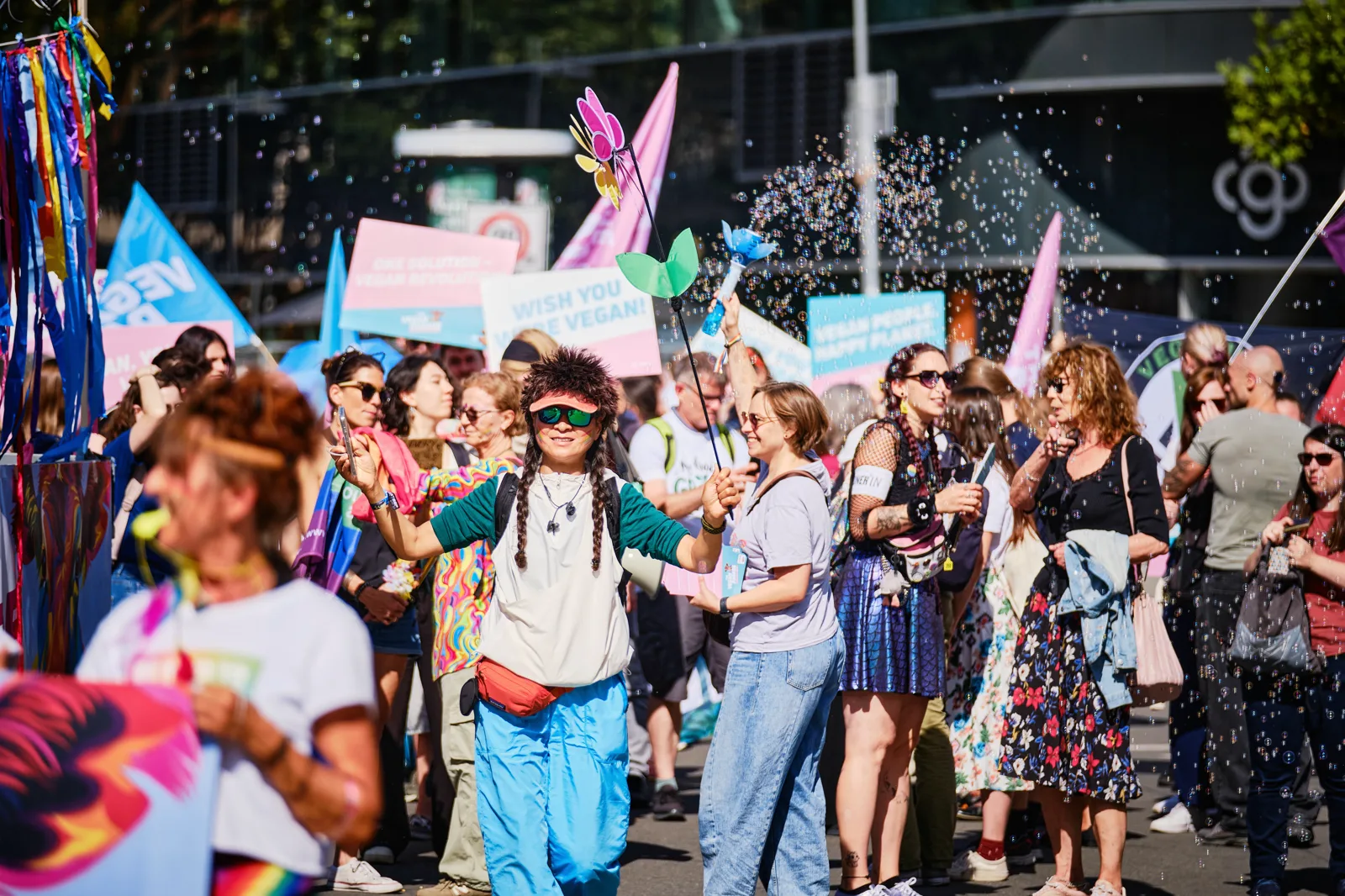 Tanzende Menschen mit bunten Schildern und Seifenblasen bei The Vegan Parade